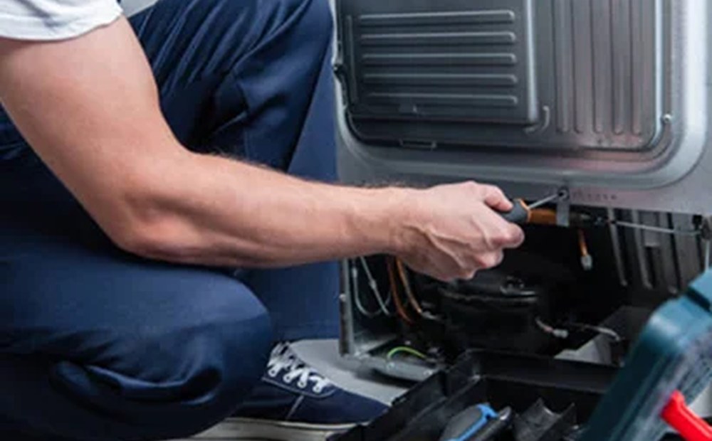 Мастер ремонтирует холодильник